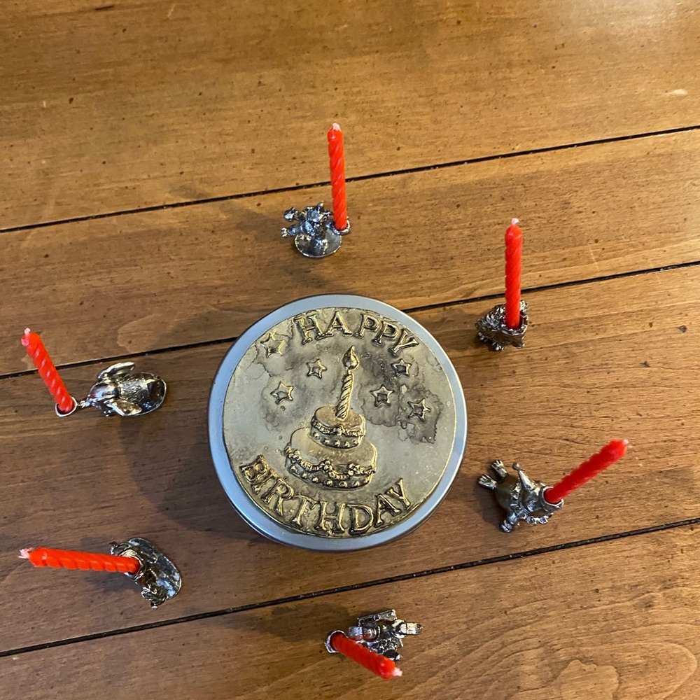 Set of animal candle holders stored in a metal tin.